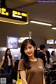 A woman standing in an airport with a yellow bag.