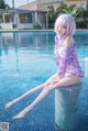 A woman sitting on the edge of a swimming pool.