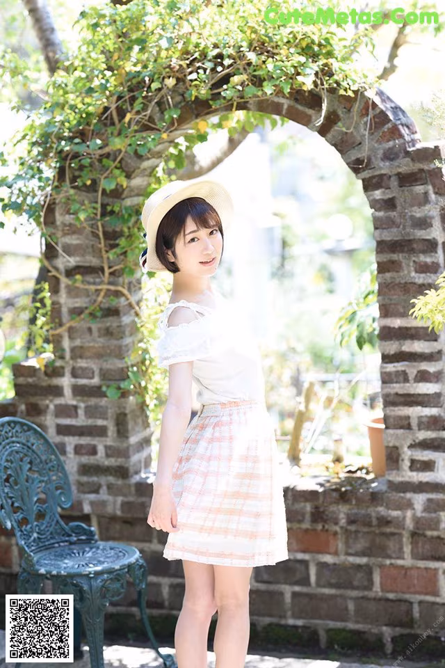 A woman in a white shirt and a pink skirt posing for a picture.