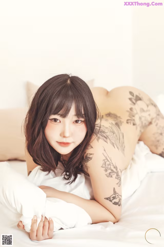 A woman laying on a bed with a tattoo on her back.