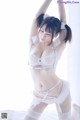 A woman in a white lingerie posing on a bed.